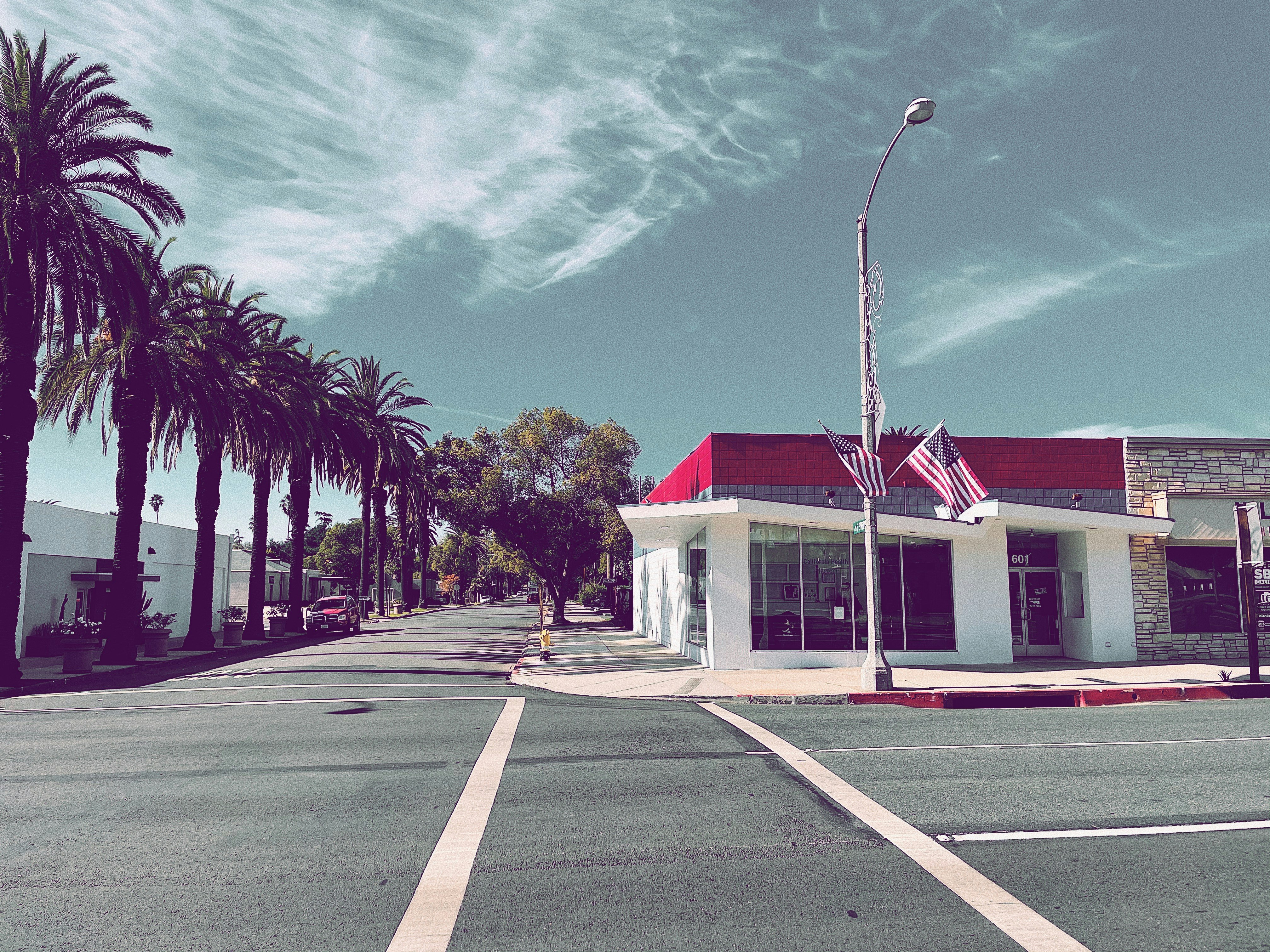 white and red house near green palm trees under blue sky during daytime